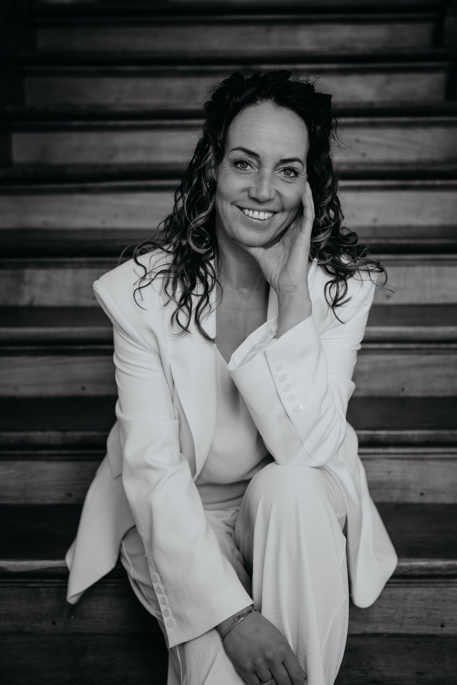 Minimalist portrait shoot featuring a woman in cream blazer sitting on wooden chair.
