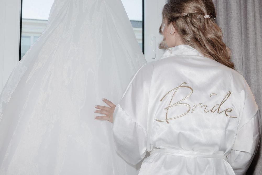 Braut Lisa im Satin-Morgenmantel mit einem Glas Sekt beim Getting-ready – standesamtliche Trauung in Duisburg-Mitte.