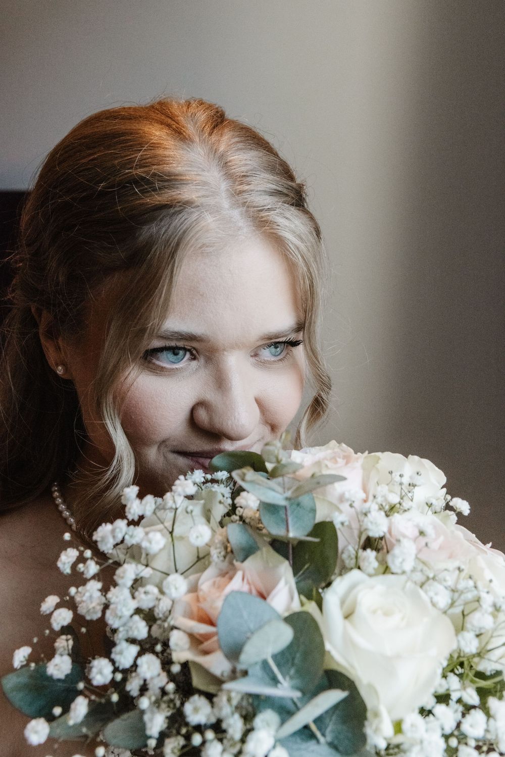 Natürliches Brautportrait: Lisa lächelt mit ihrem Brautstrauß aus Rosen und Eukalyptus – Hochzeit am Standesamt Duisburg-Mitte.