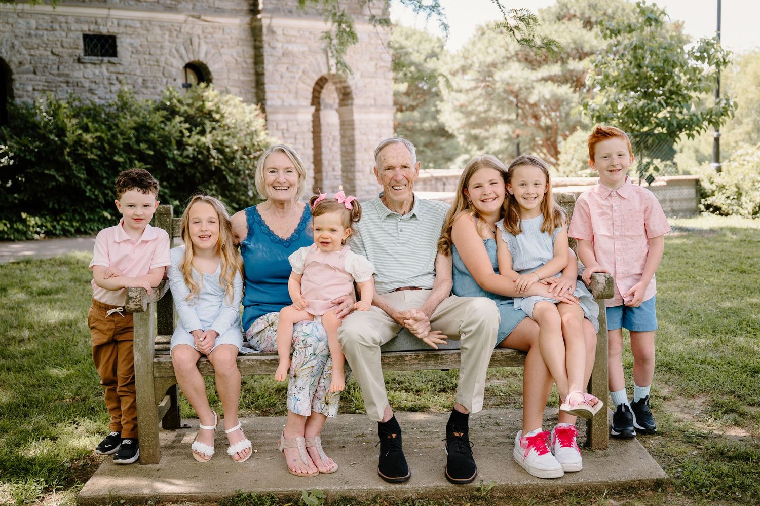 Family portrait of grandparents with six grandchildren sitting on a bench outdoors in Ault Park Cincinnati OH by K Herman Photography