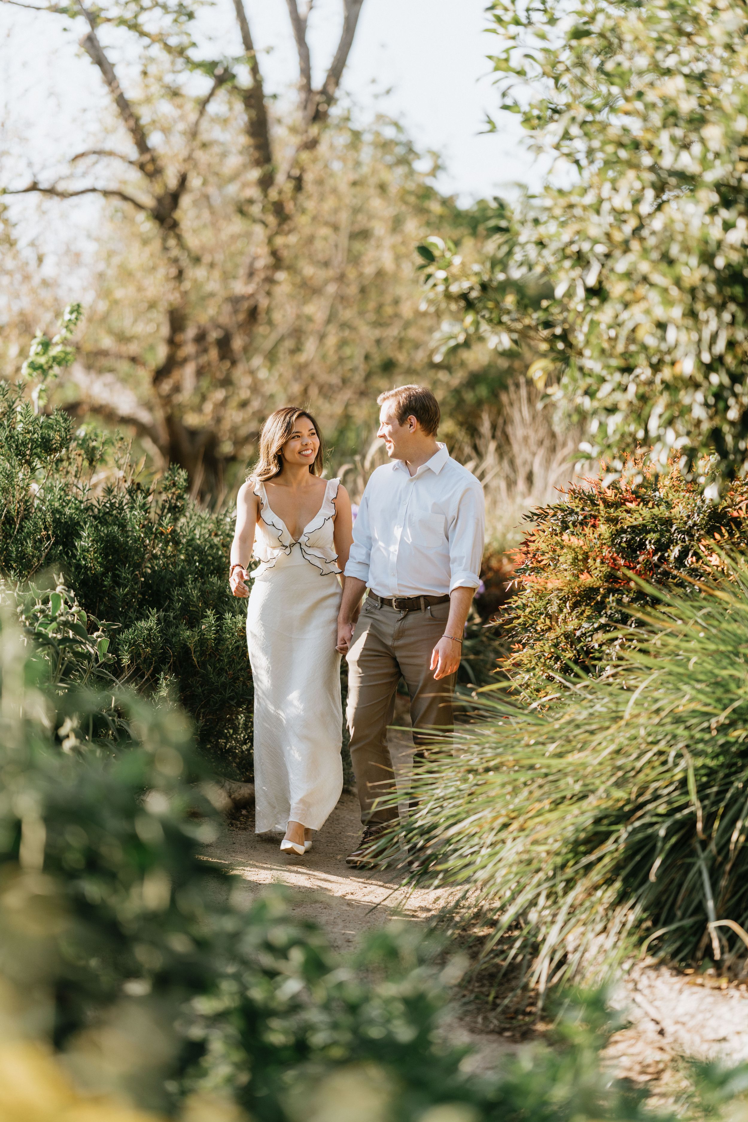 Mariel and Jeff walking hand in hand through the Los Angeles County Arboretum gardens.