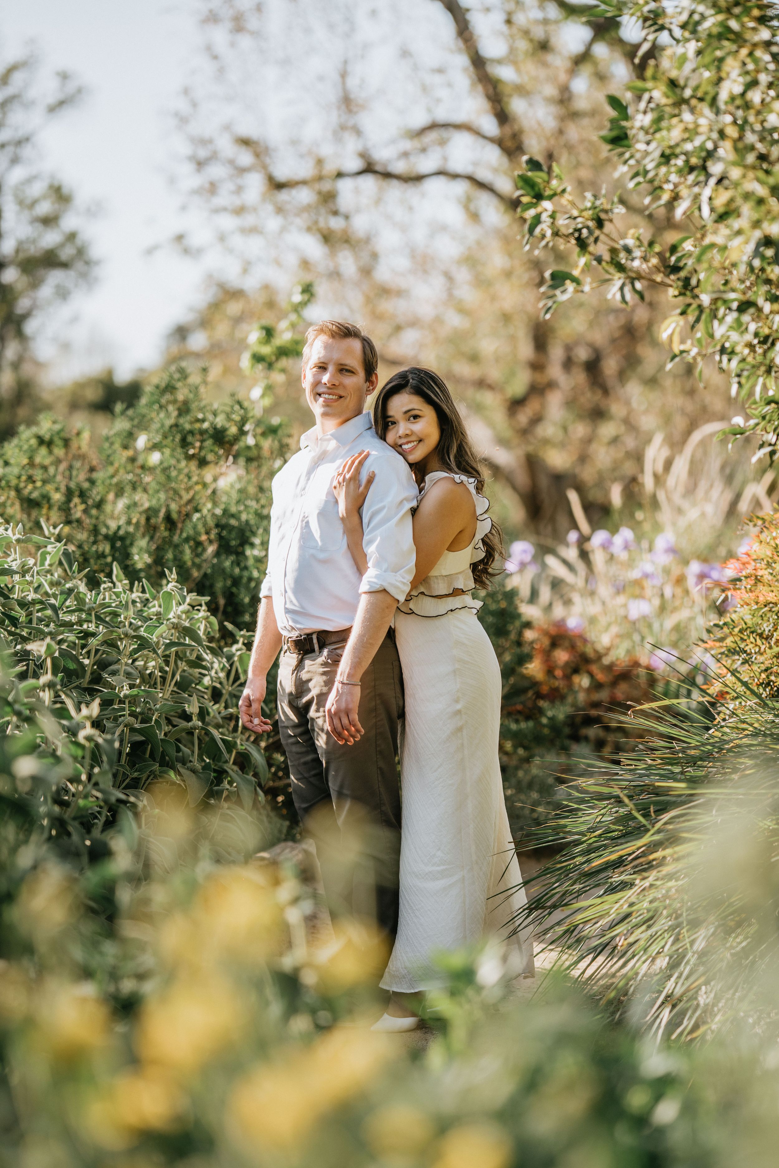 Mariel and Jeff posing among lush gardens at the Los Angeles County Arboretum.