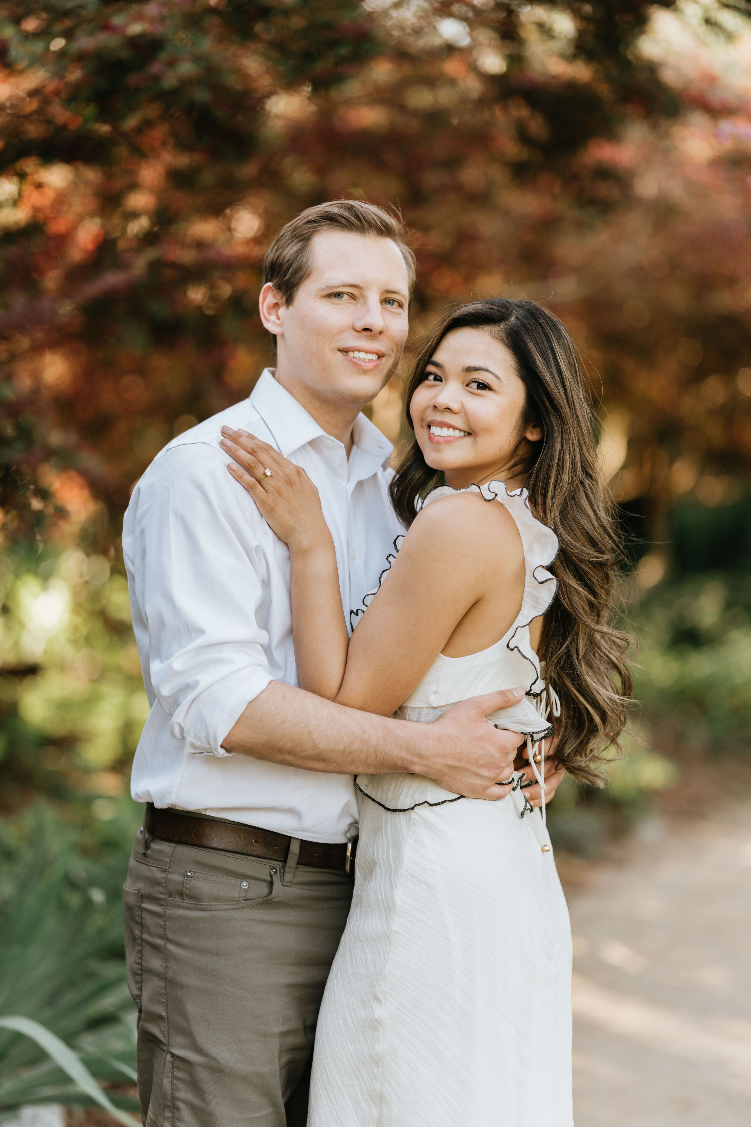 Romantic engagement portrait of Mariel and Jeff beneath colorful spring foliage.