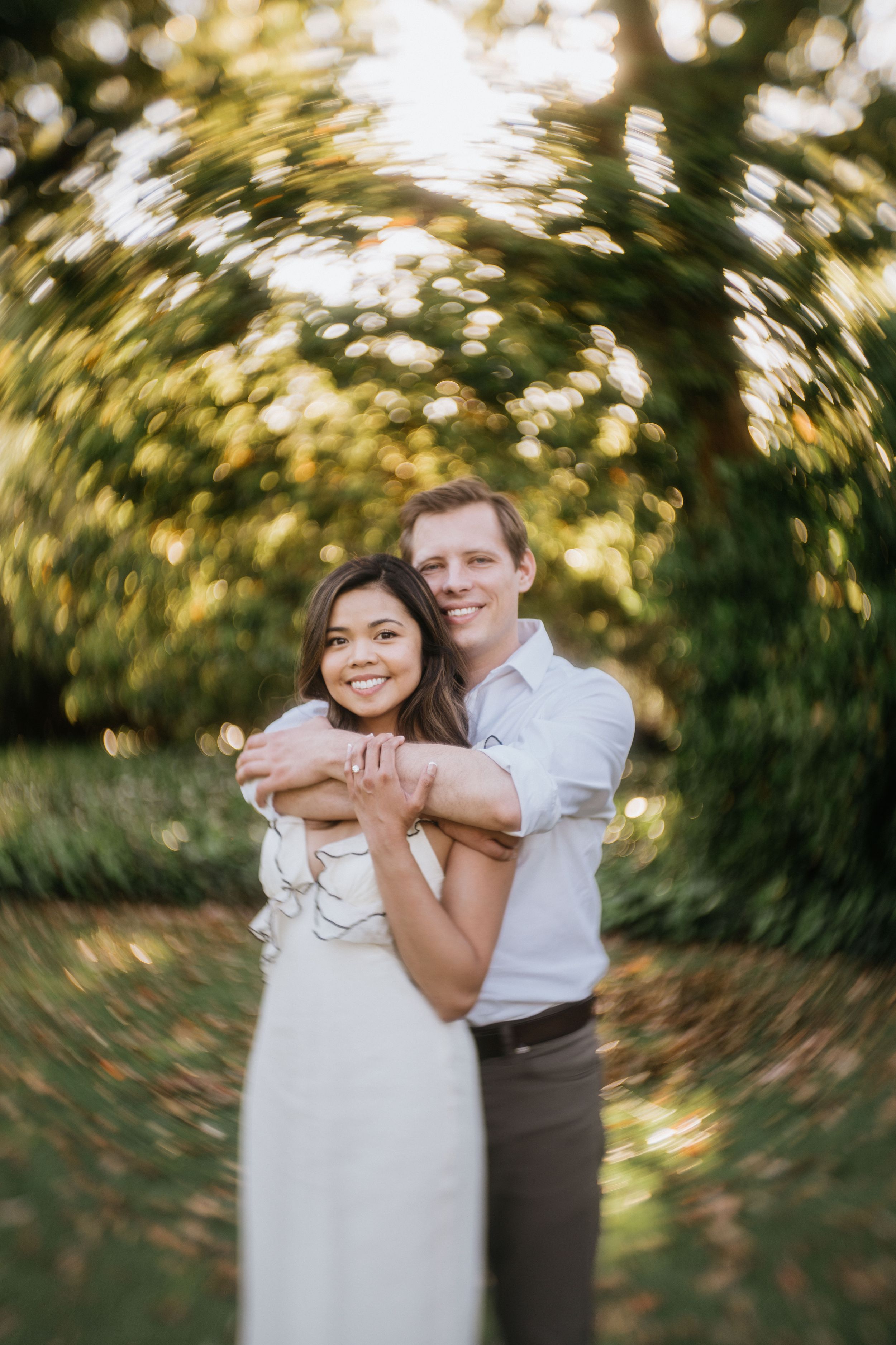 Mariel and Jeff embracing during their Arboretum engagement session at golden hour.