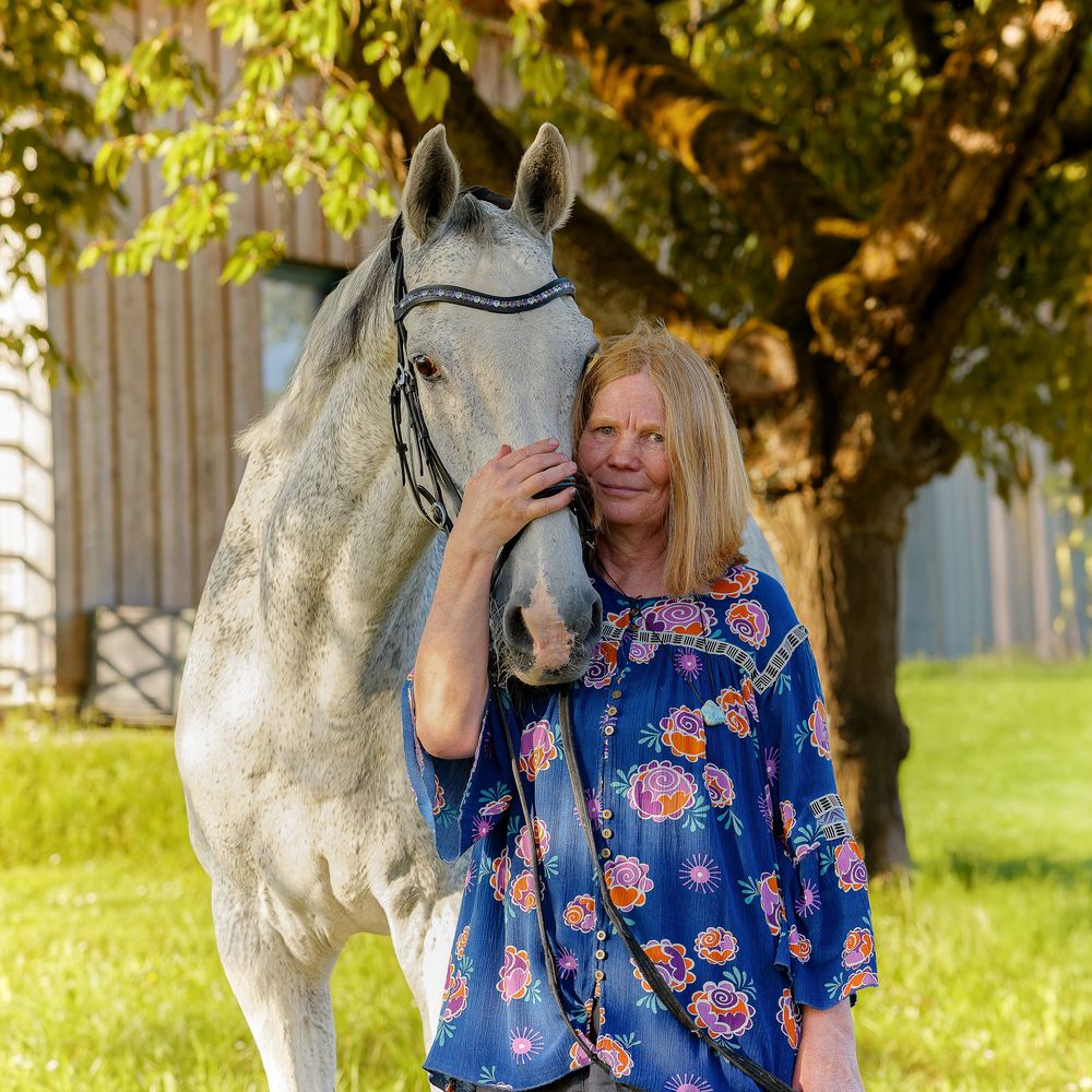 Frau und weißes Pferd im Schatten von Bäumen. Professionelle Tierporträts von Lichtkapsel im 60km-Umkreis Erlangen.