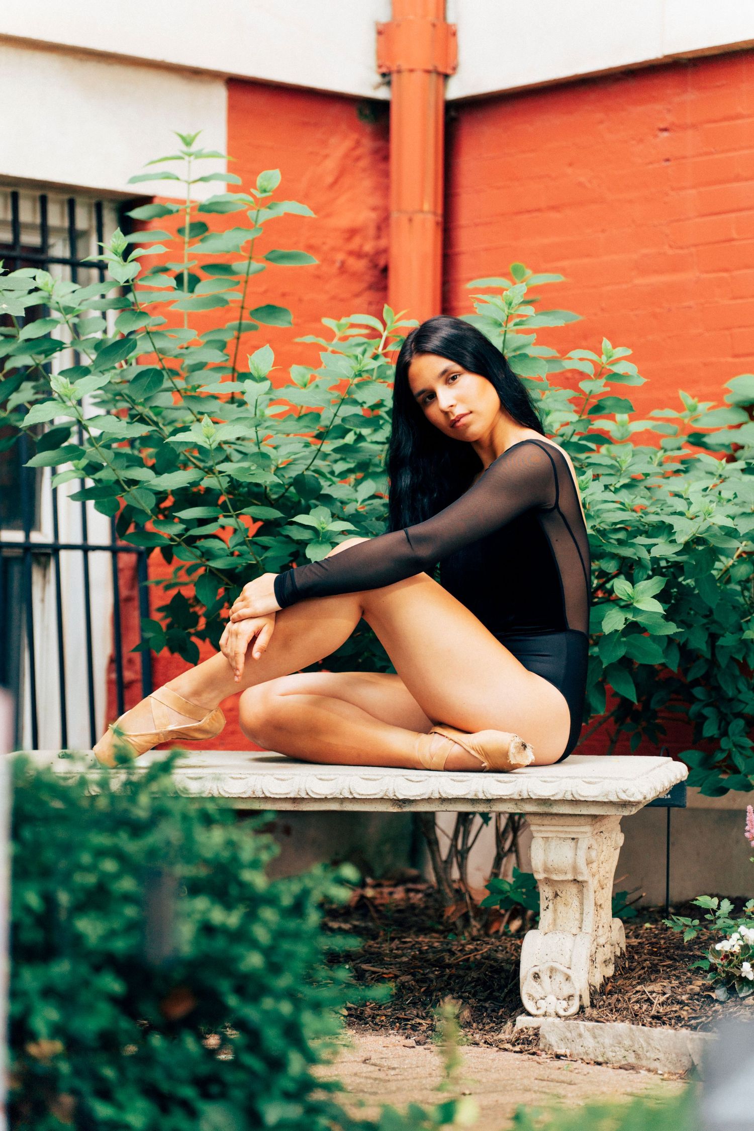 Professional dancer senior portrait of a teen ballerina in a black bodysuit seated on a stone garden bench in pointe shoes, Crown Point phot