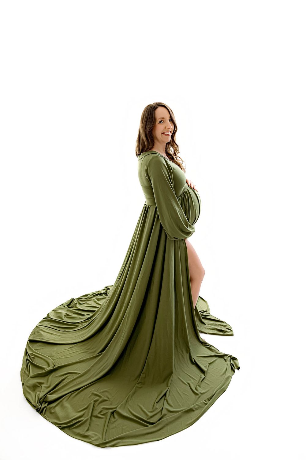 Pregnant woman in elegant olive green maternity gown with flowing train, posing against white background.