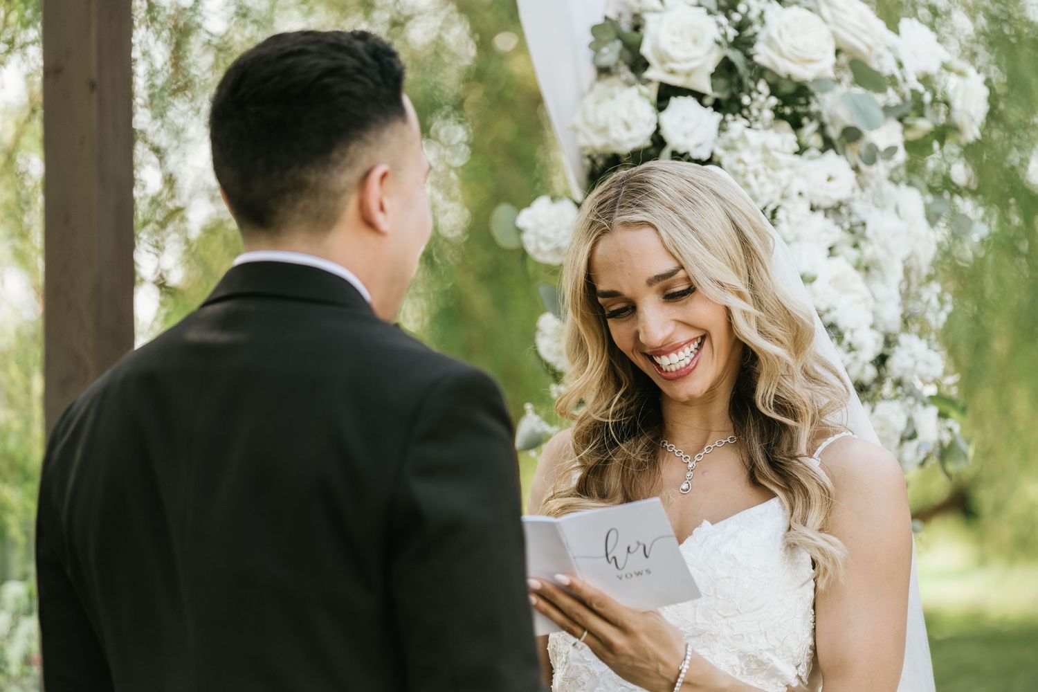 Gabriella smiling at Paul while reading her wedding vows