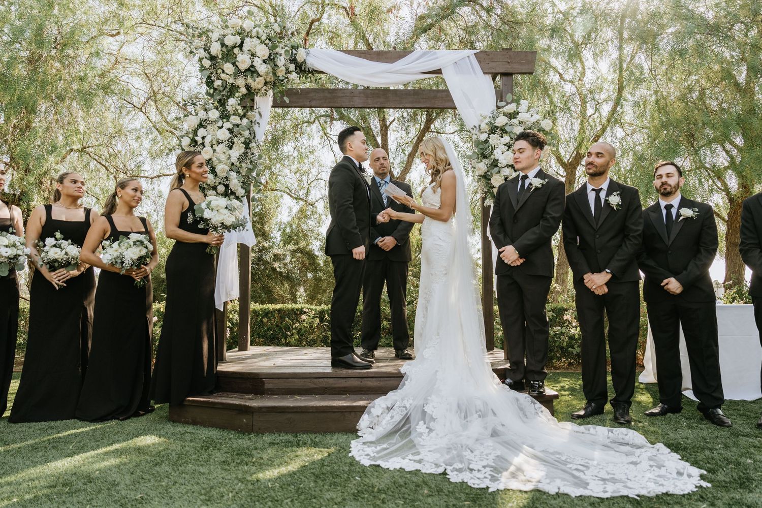 Gabriella and Paul exchanging vows beneath a floral ceremony arch