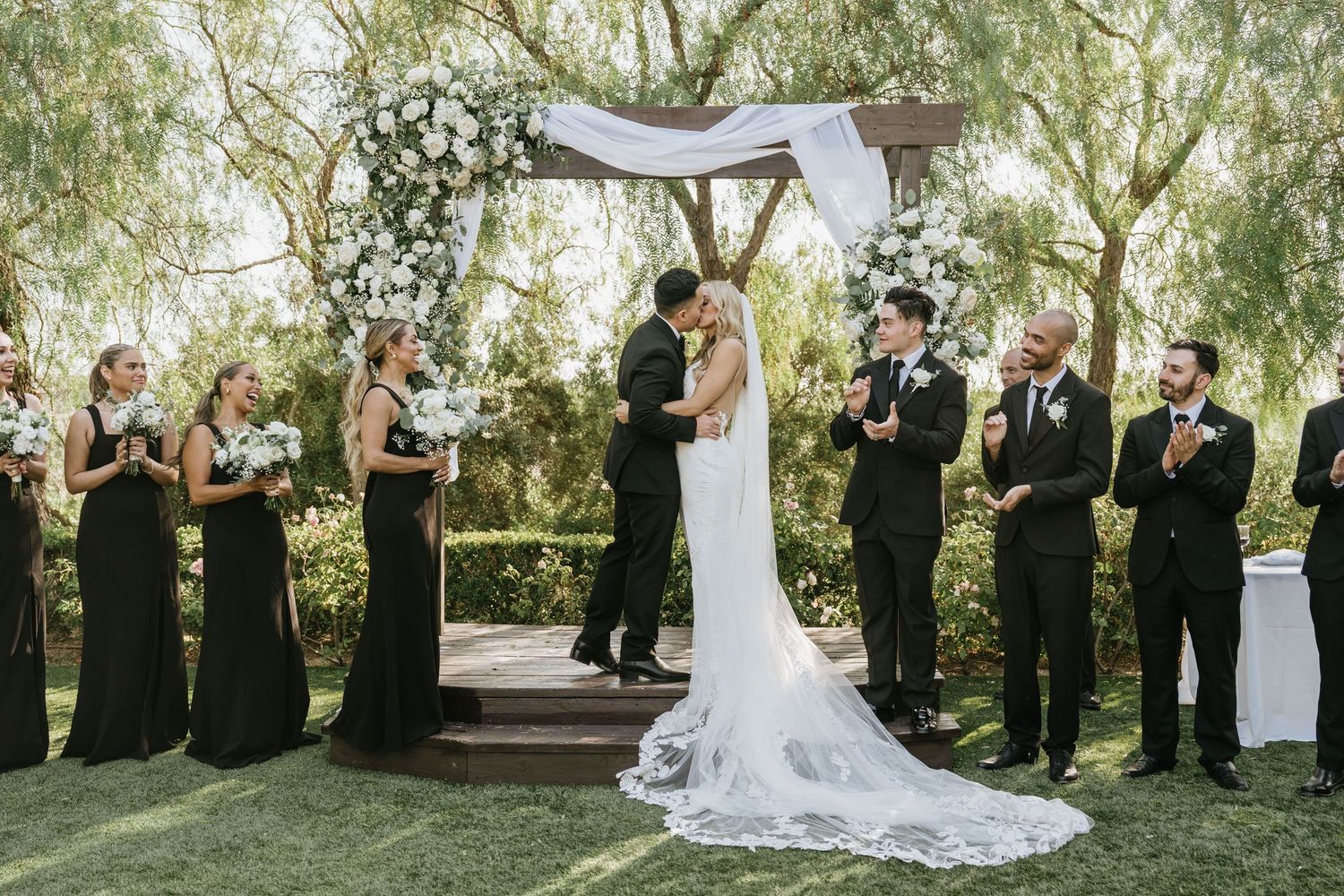 Gabriella and Paul sharing their first kiss beneath the floral ceremony arch at Falkner Winery