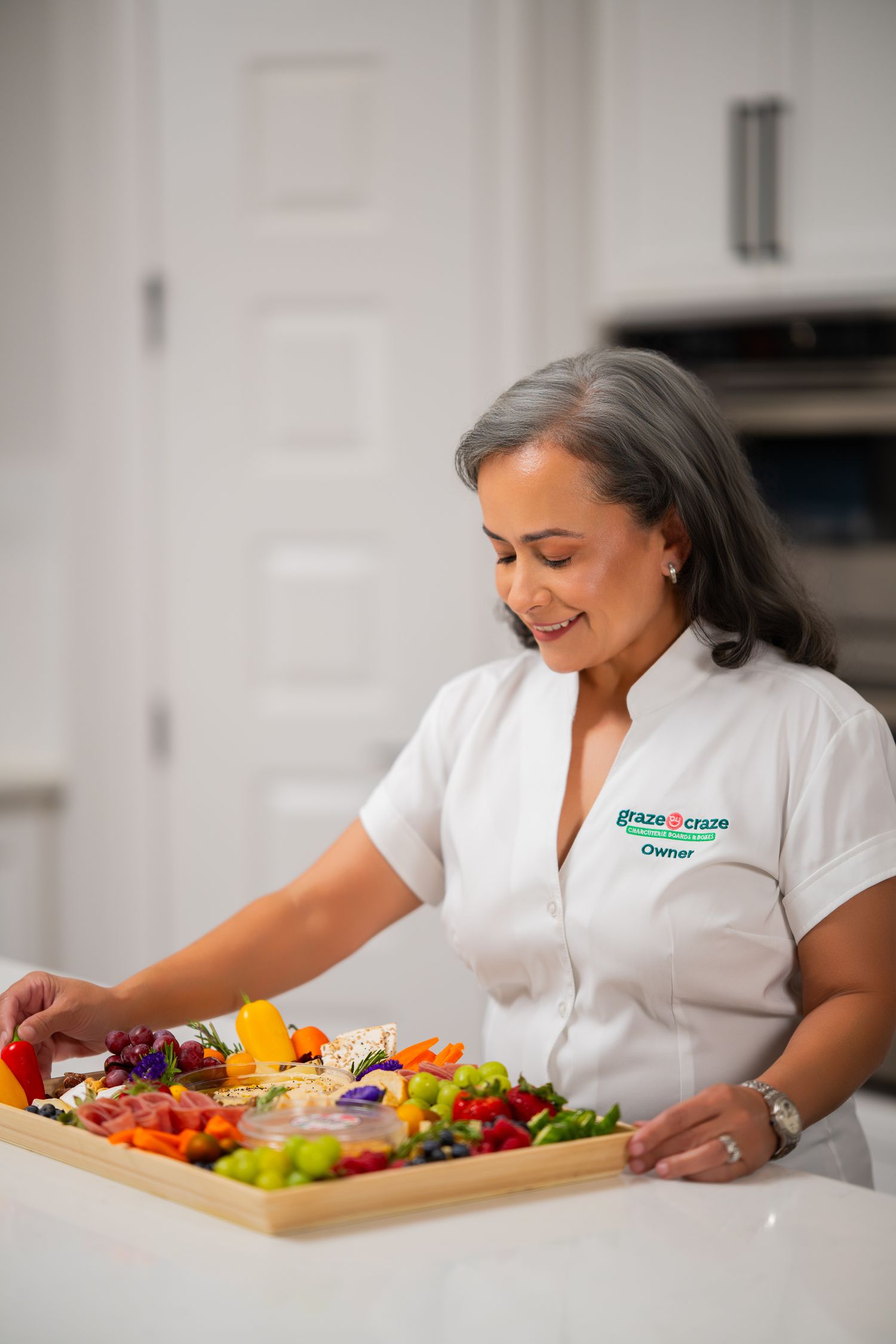 Orlando small business branding photographer Ray Alvarez — Graze Craze Orlando owner with handcrafted charcuterie board in kitchen setting