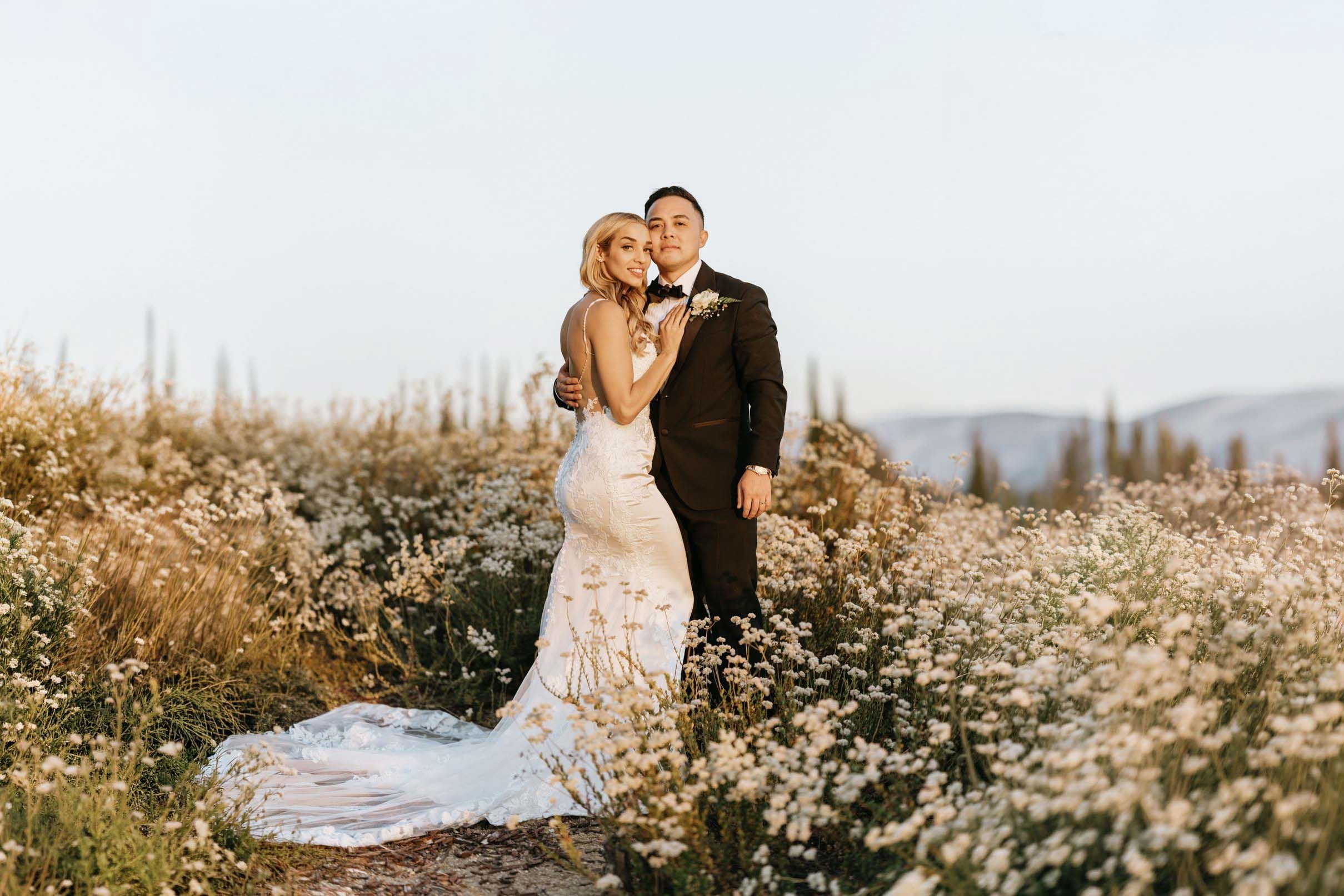 Bride and groom sharing a golden hour portrait surrounded by blooming wildflowers at Falkner Winery in Temecula, California.