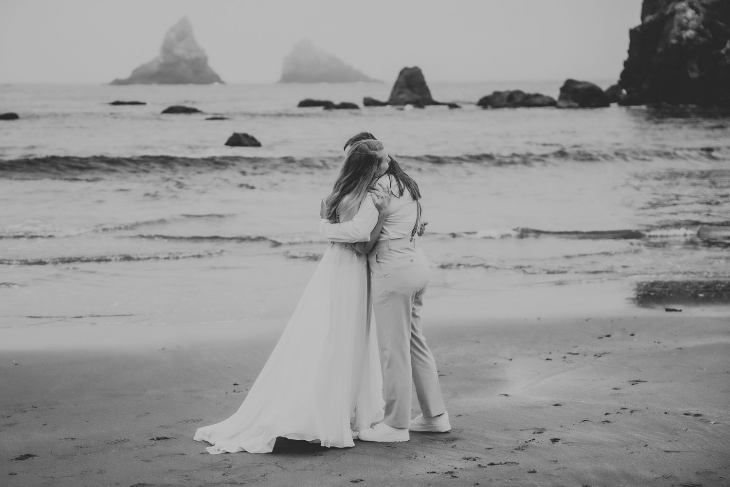 Two brides embrace after exchanging vows on their elopement day on the Oregon coast