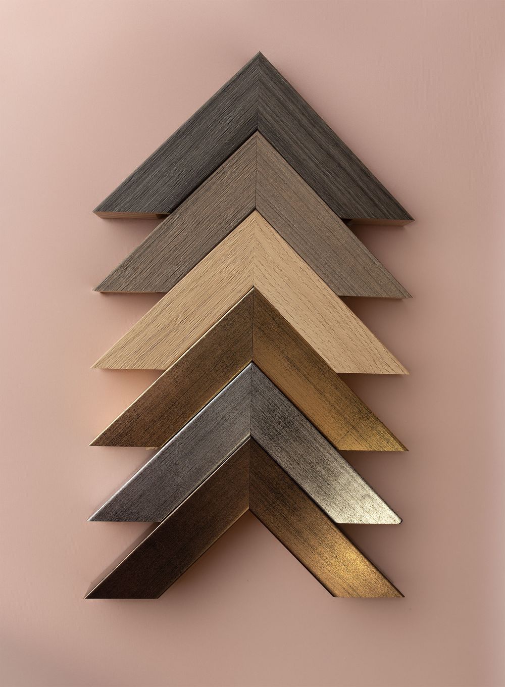 Five chevron-shaped picture frame corners in varied wood tones from dark gray to gold display Available at Keepsakes in Oban