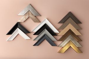 Assorted picture frame corner samples in silver, black, white, gray, and gold displayed in chevron pattern at Ada Studio Oban.