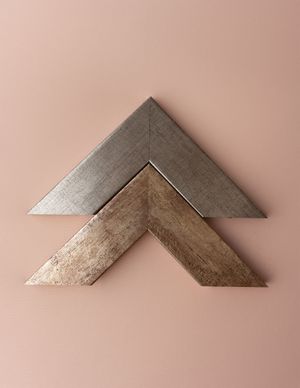 Two chevron-shaped picture frame corners in silver and gold metallic finishes available at Ada Studio Oban.