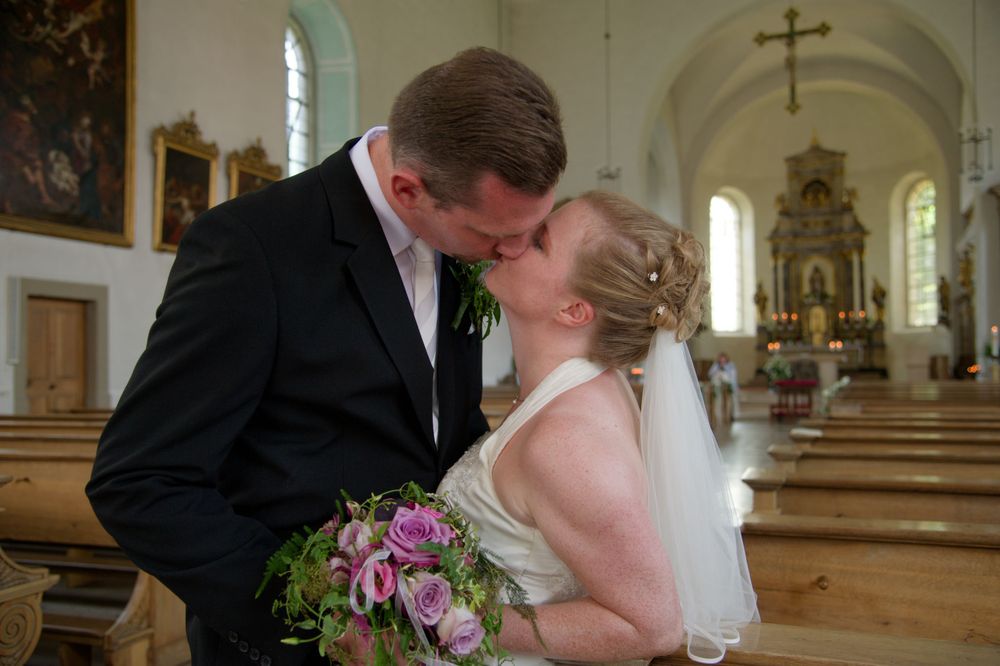 Brautpaar küsst sich innig im Kirchenschiff einer Kirche in Eggolsheim. Romantische und ungestellte Hochzeitsfotografie.