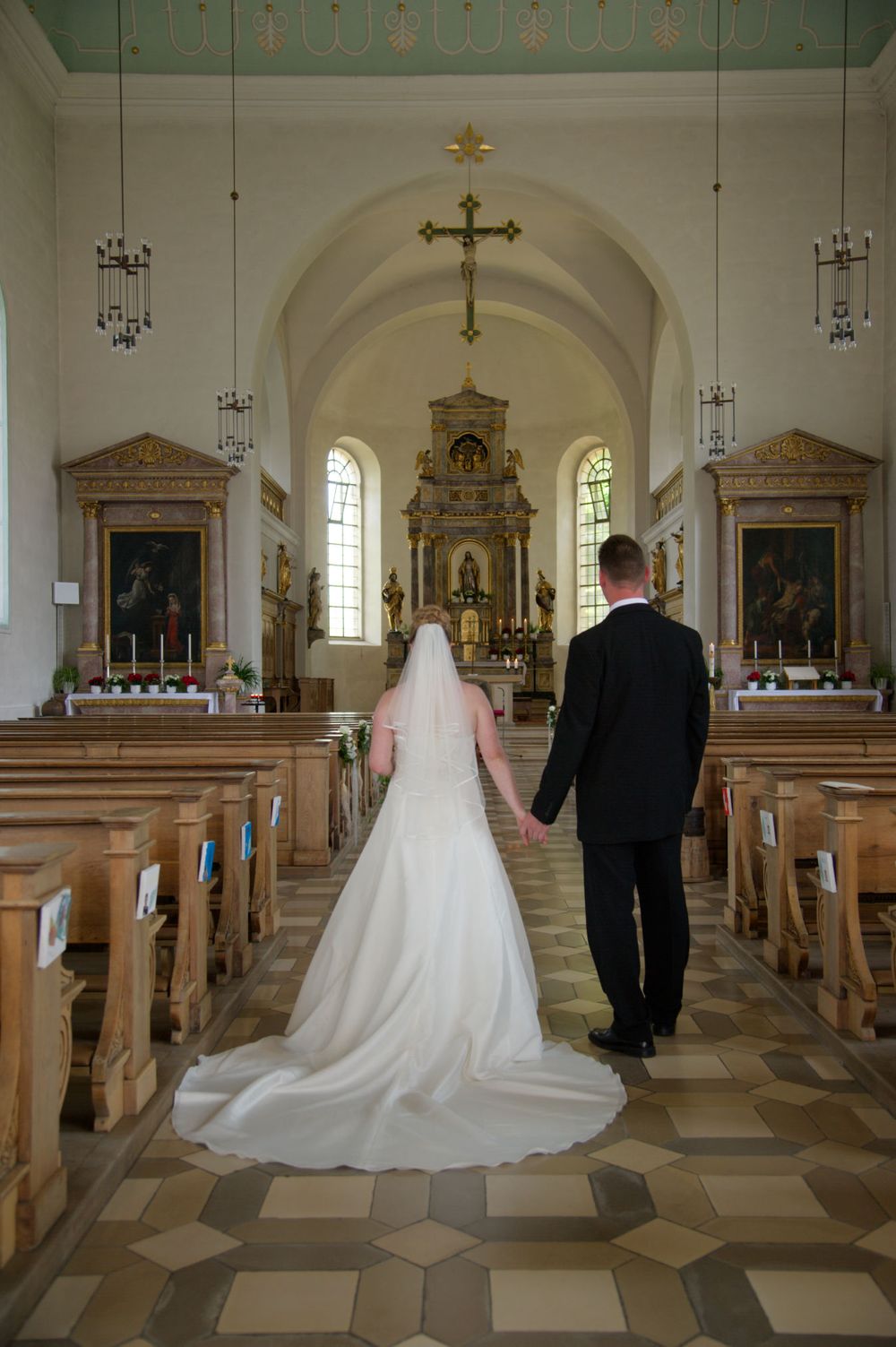 Braut und Bräutigam gehen Hand in Hand durch den Mittelgang der Kirche. Authentische Hochzeitsreportage in Eggolsheim.