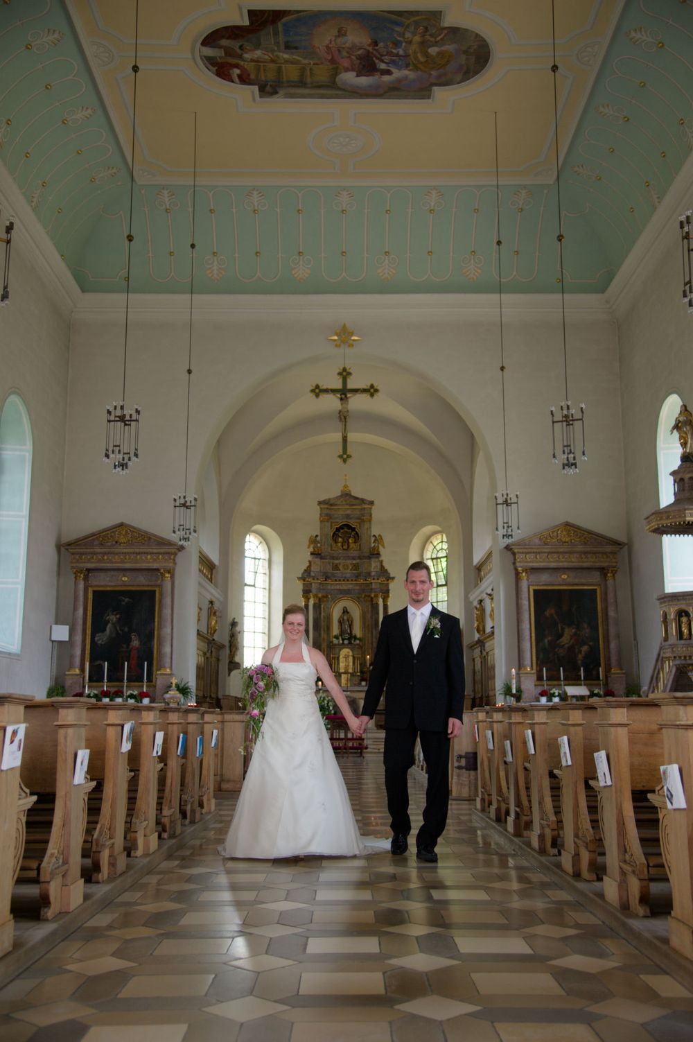 Brautpaar schreitet nach der Trauung durch das Kirchenschiff. Emotionale Hochzeitsfotografie in einer Kirche in Eggolsheim.
