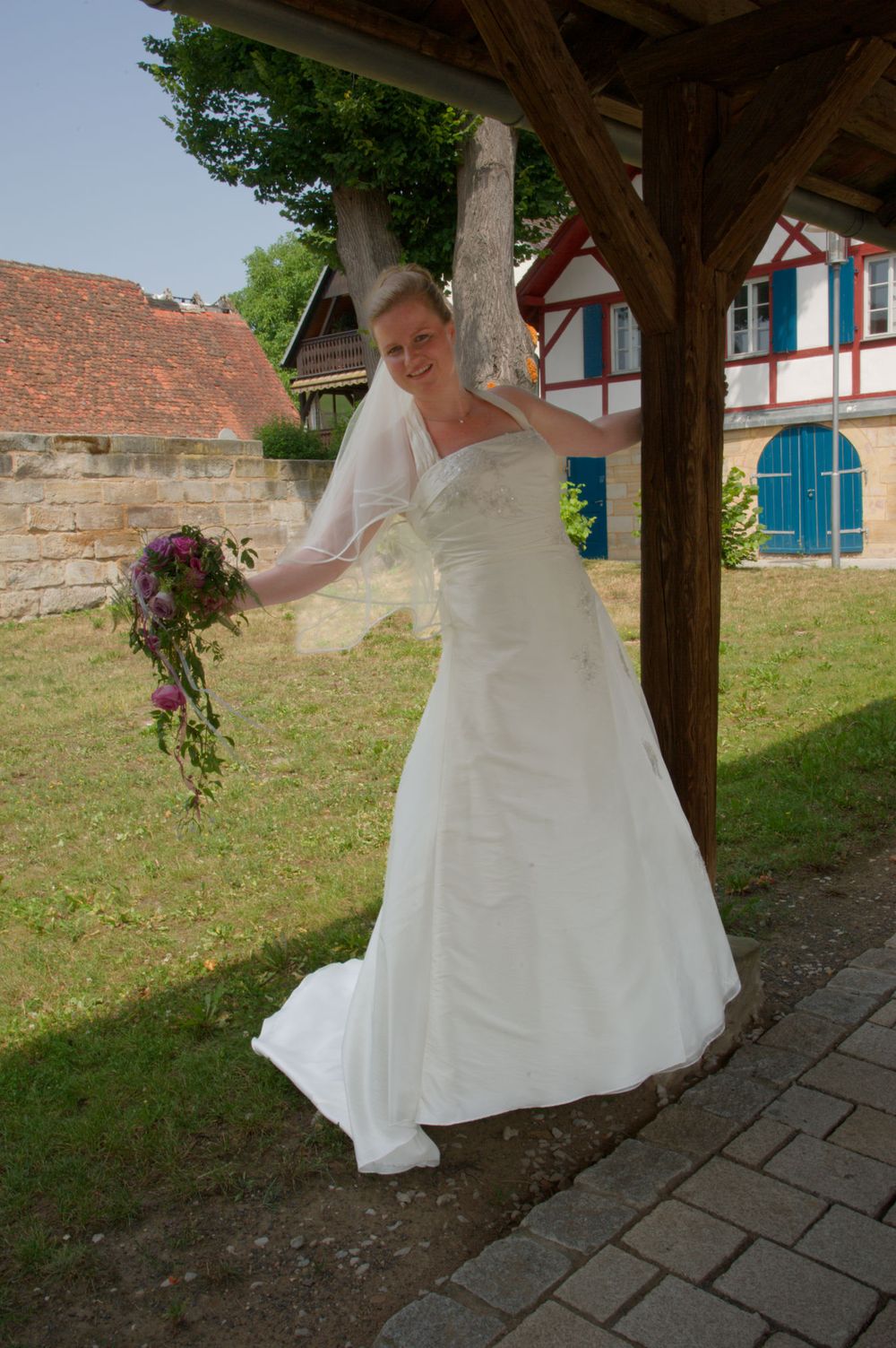 Braut posiert elegant vor einem alten Holzbogen in Eggolsheim. Ästhetisches Brautporträt von der Lichtkapsel.