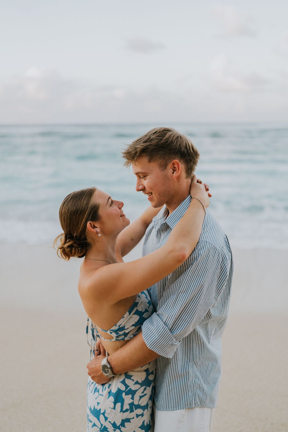 Couple celebrating engagement at Melasti Beach with ocean backdrop.