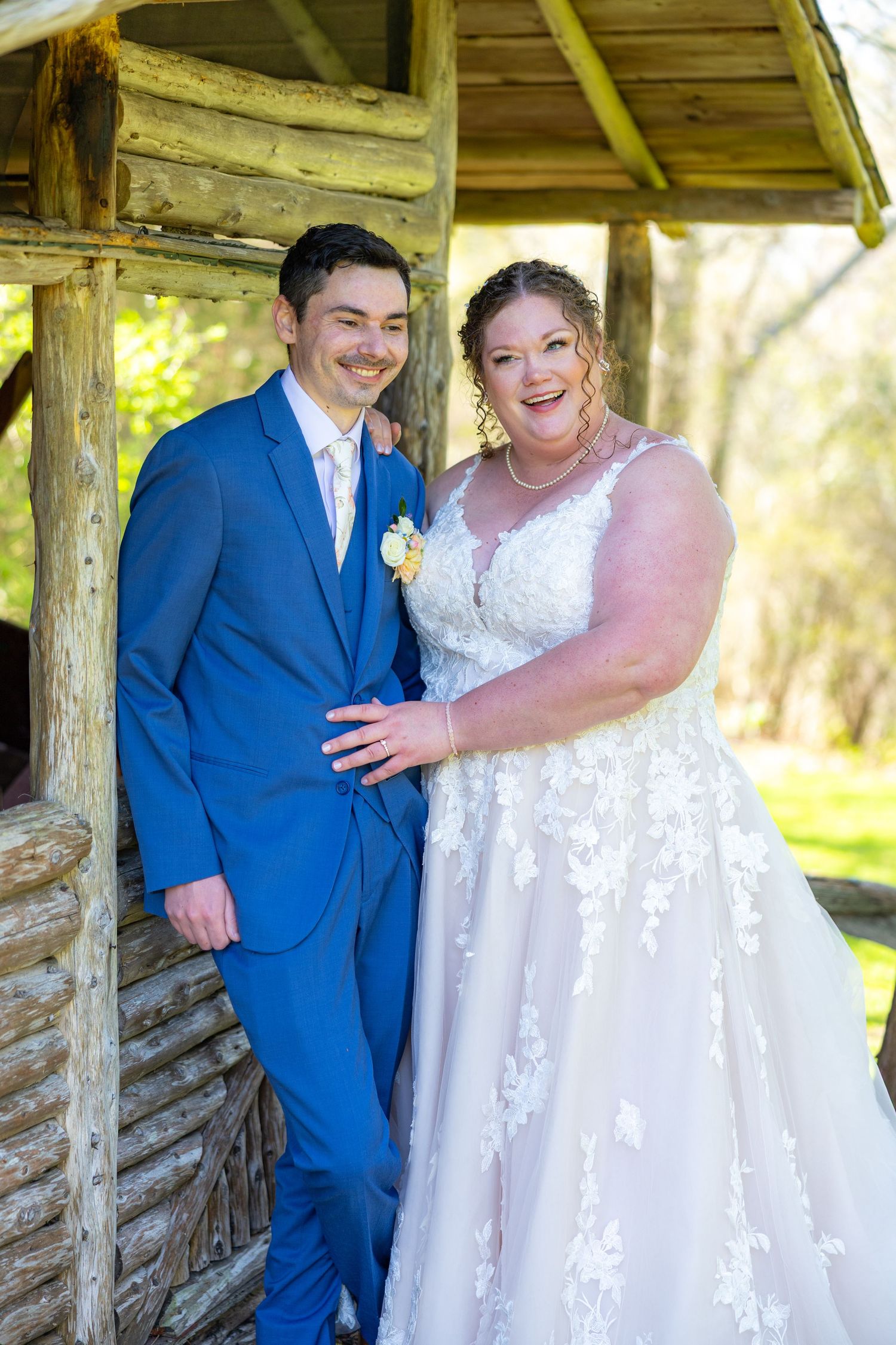 A couple shares a romantic moment under a rustic wooden gazebo during their wedding day celebration.