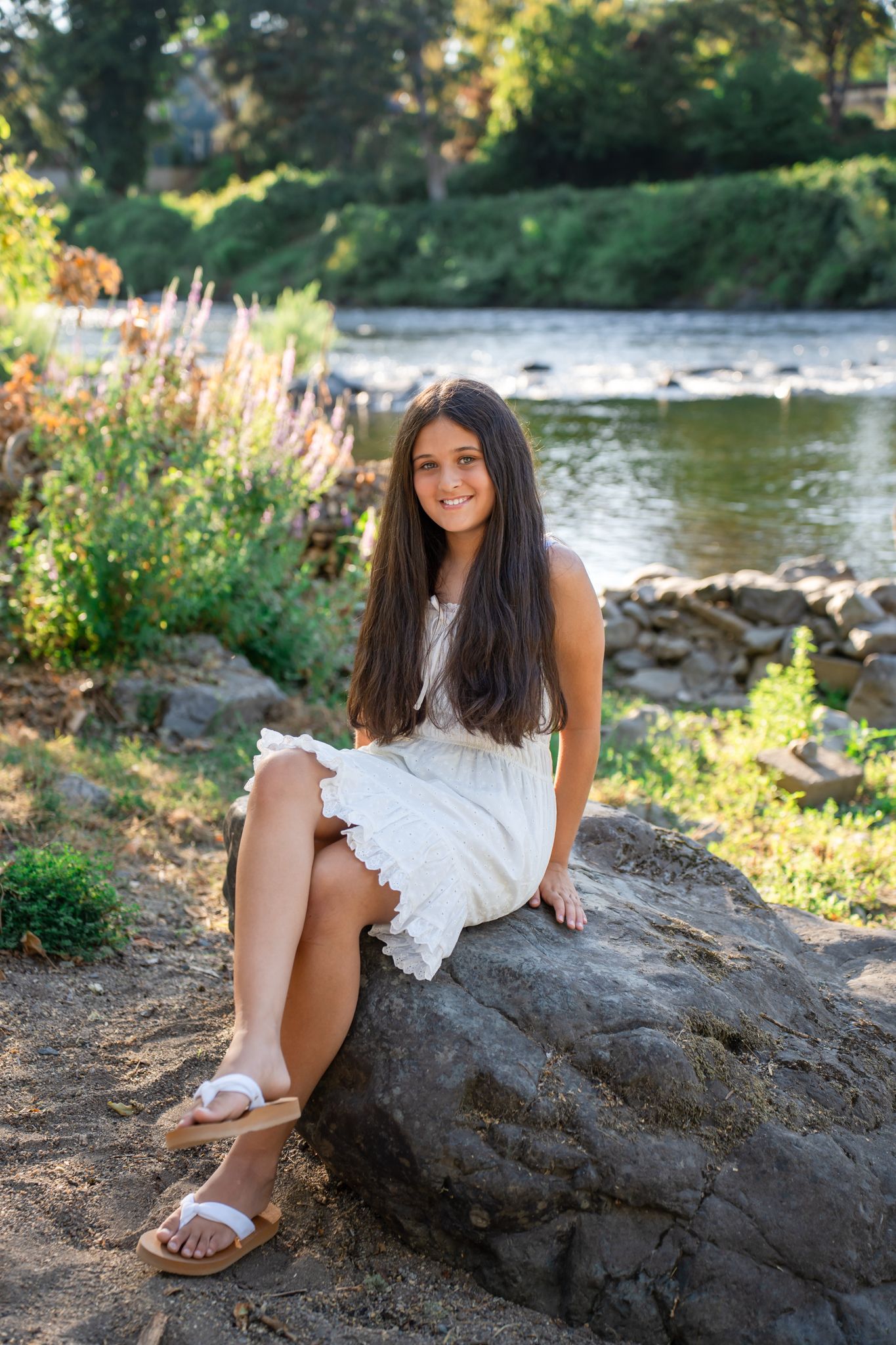 Portrait of a teen girl sitting on a rock by the river