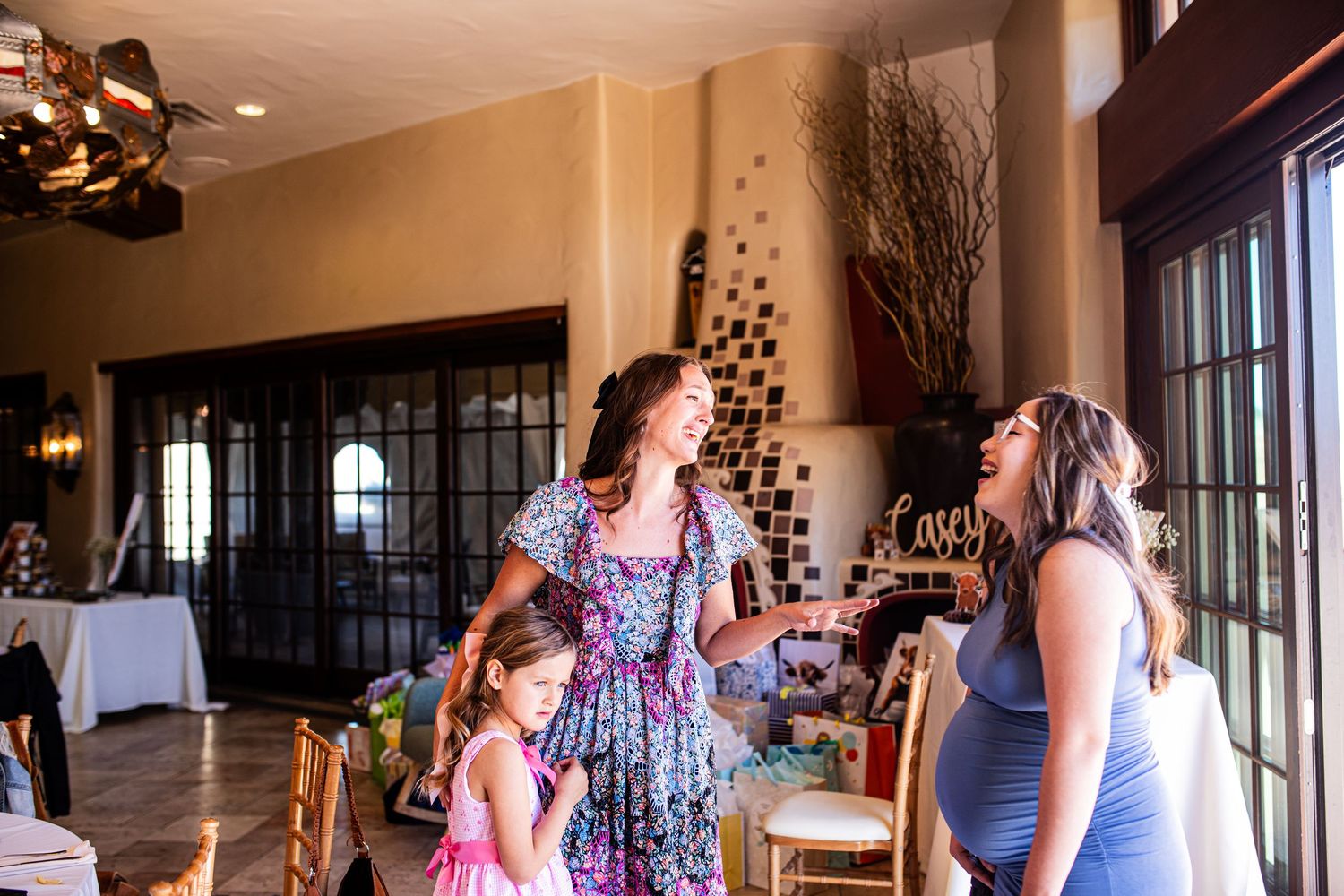 Women in floral dresses socializing at an elegant indoor venue during a special celebration event.
