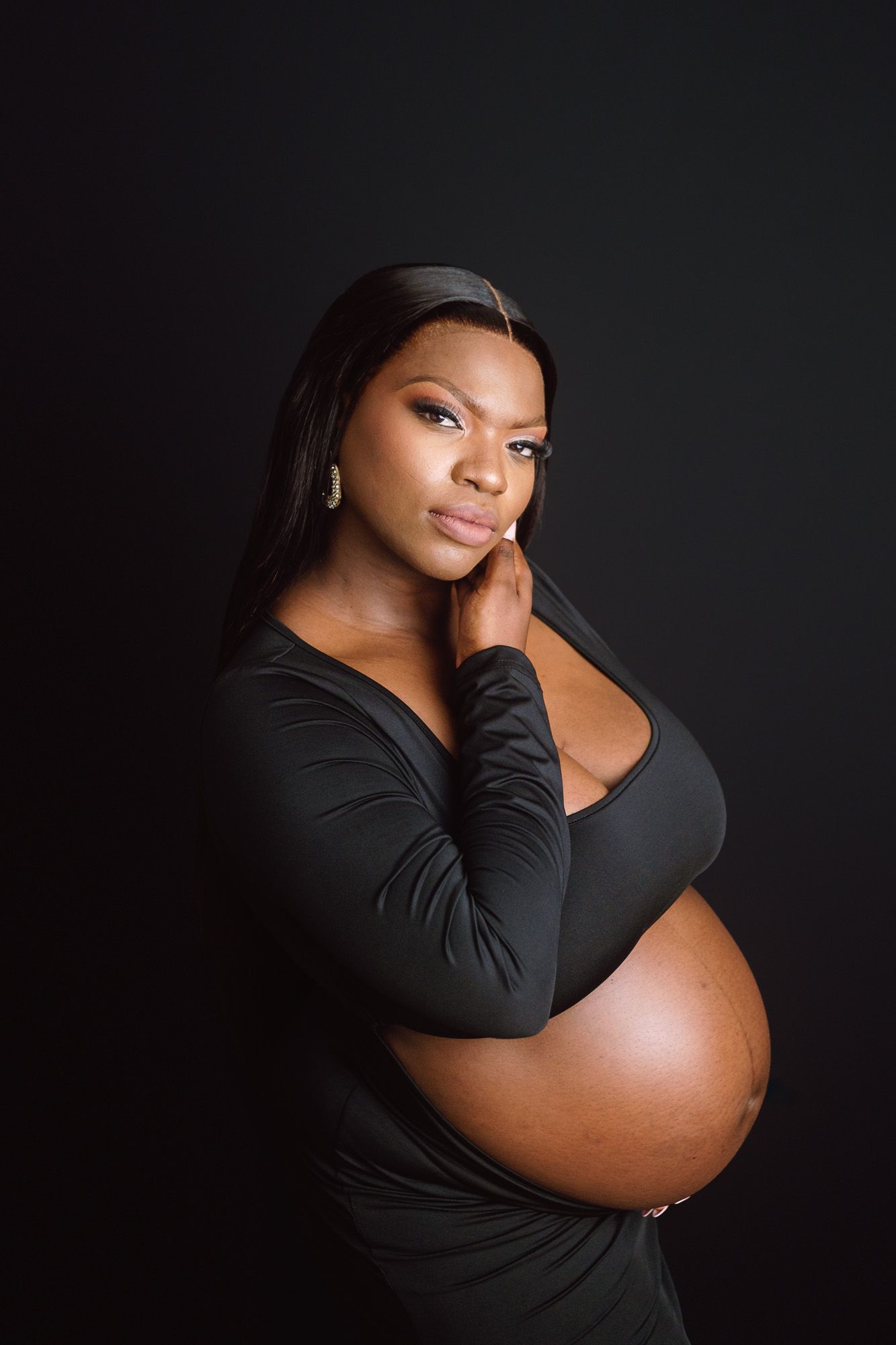 Pregnant mother posing in a studio maternity portrait on a black background