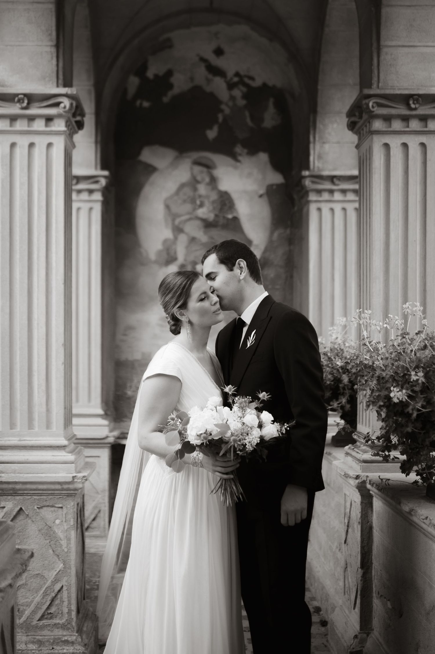 A romantic wedding couple shares a tender moment under a white parasol at golden hour.