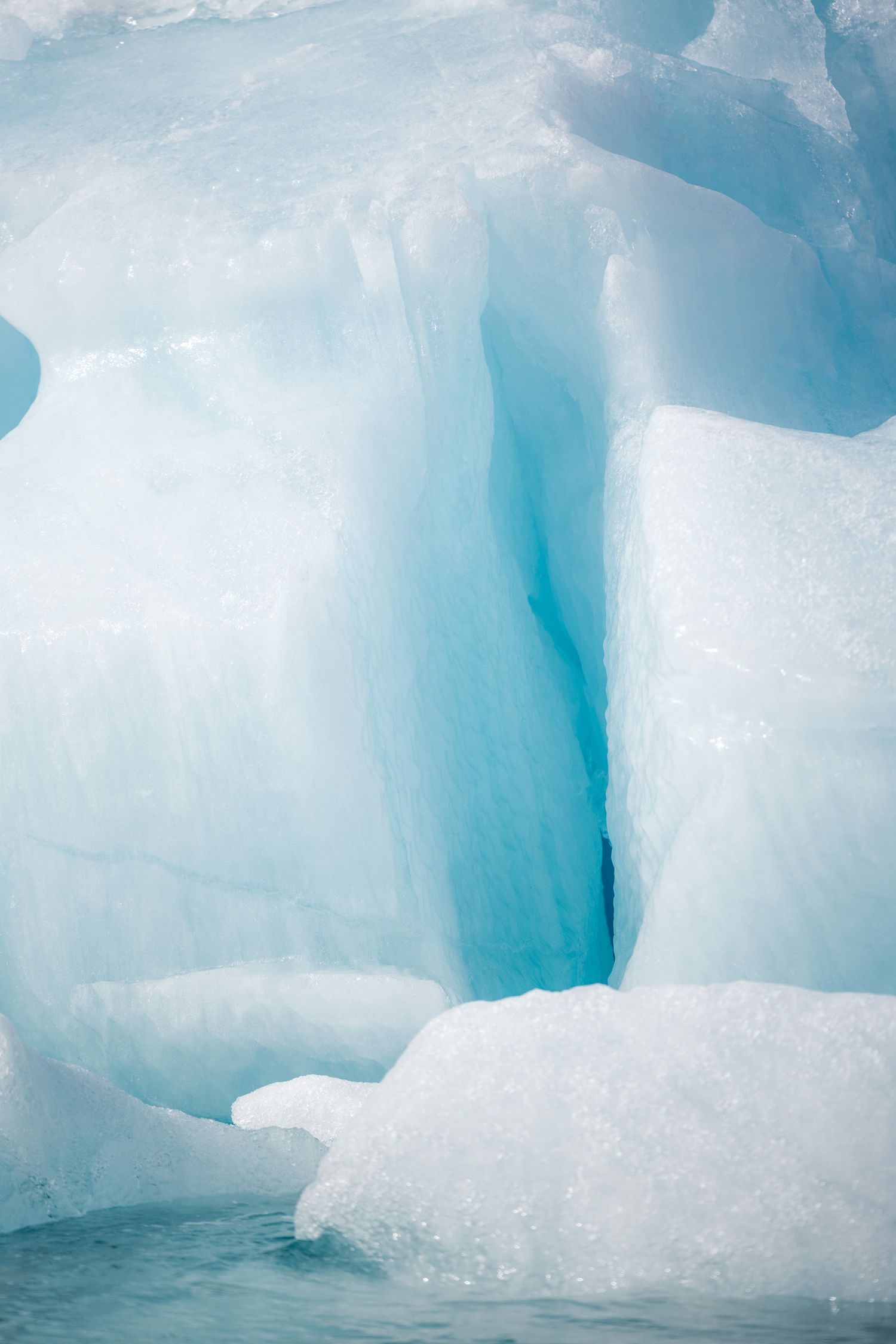 Faille verticale turquoise séparant deux pans de glace blanche dans un iceberg