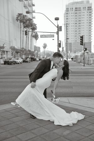 Bride and groom share a romantic dip kiss on Las Vegas Boulevard in black and white wedding photo.