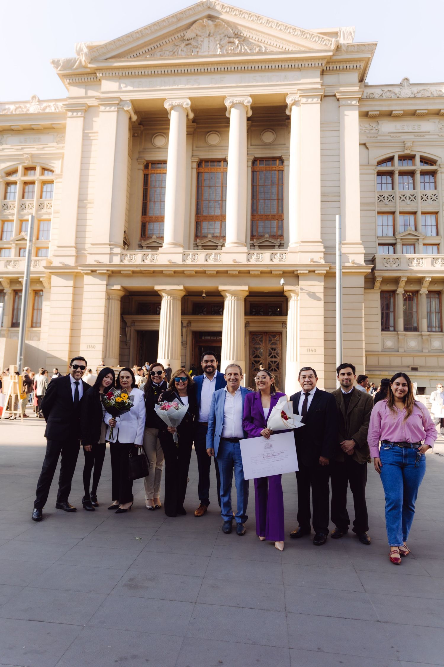 Large group of professionals pose outside impressive neoclassical building with columns.