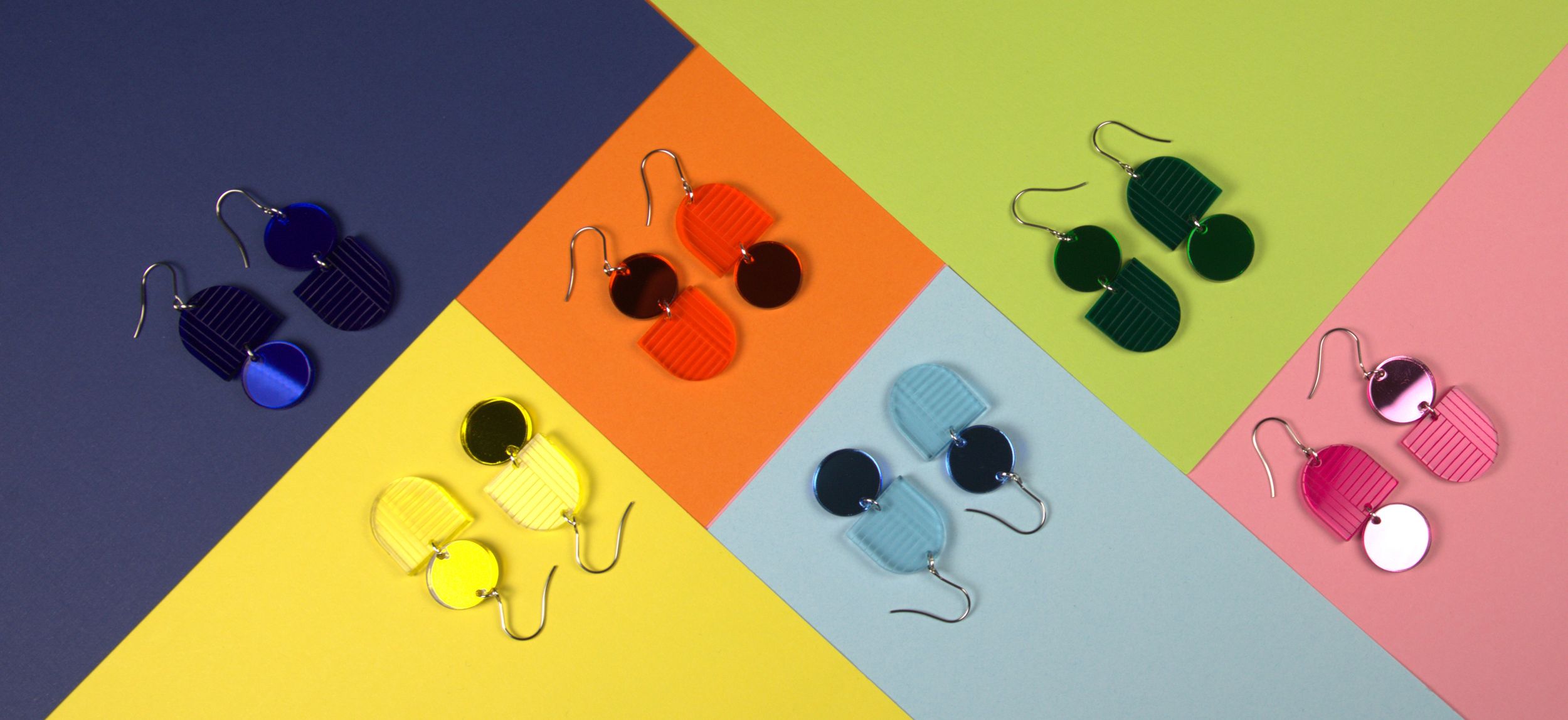 Colorful acrylic circle dangle earrings in multiple colors on geometric background.
