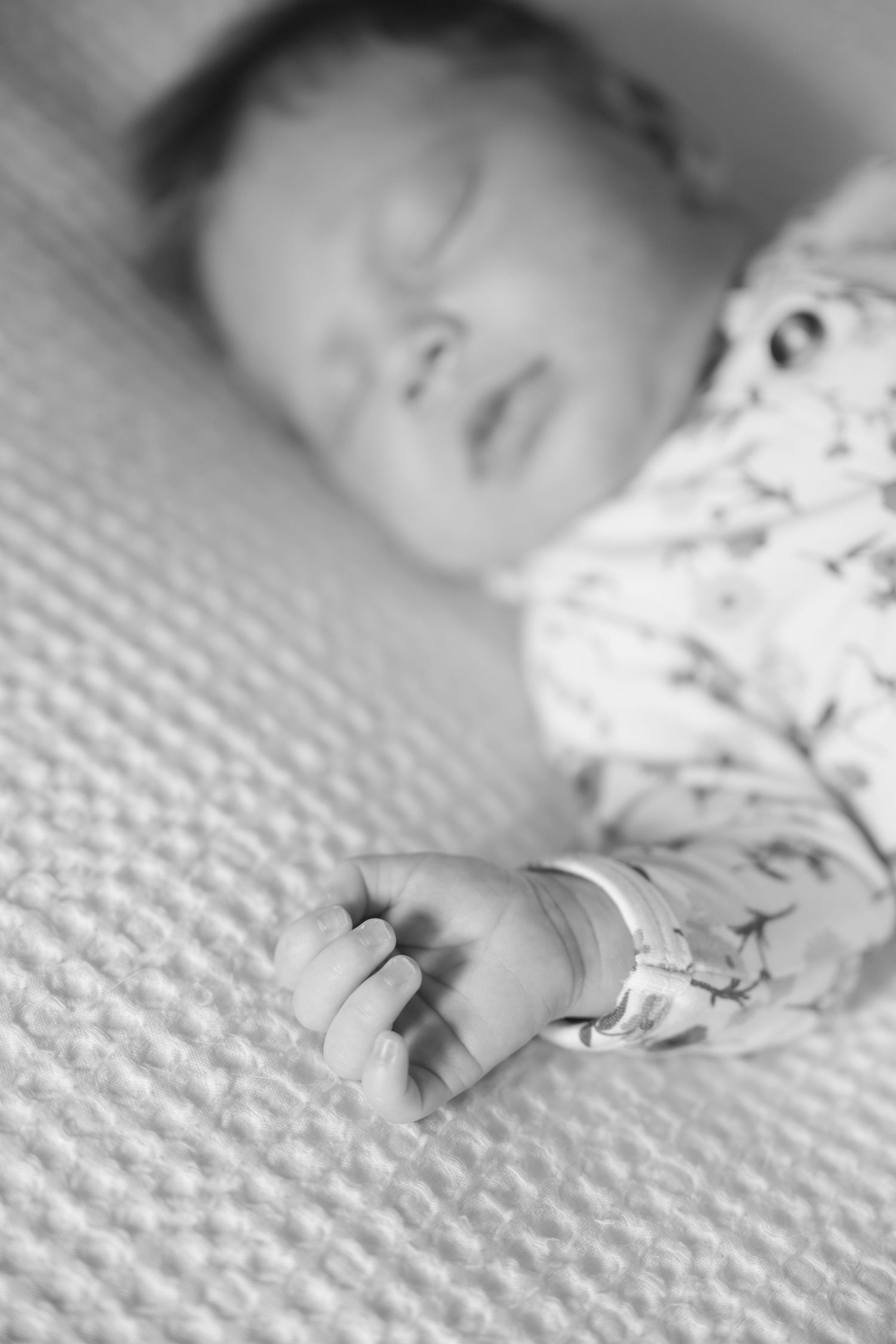 detail black and white photo of newborn baby's hand during in-home lifestyle newborn session in the Twin Cities, MN.
