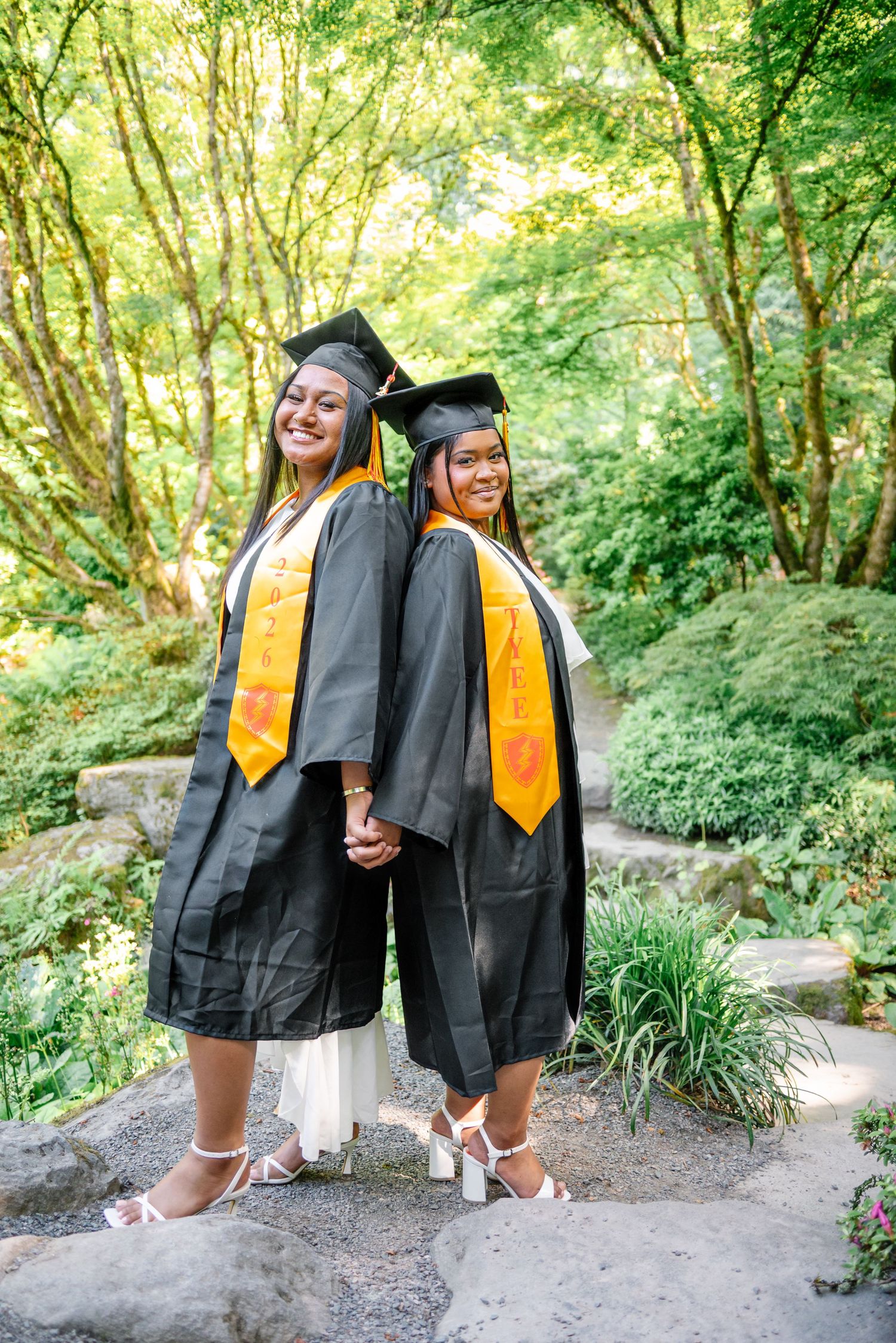 Two best friends posing together in their caps and gowns during graduation photos at Bellevue Botanical Garden