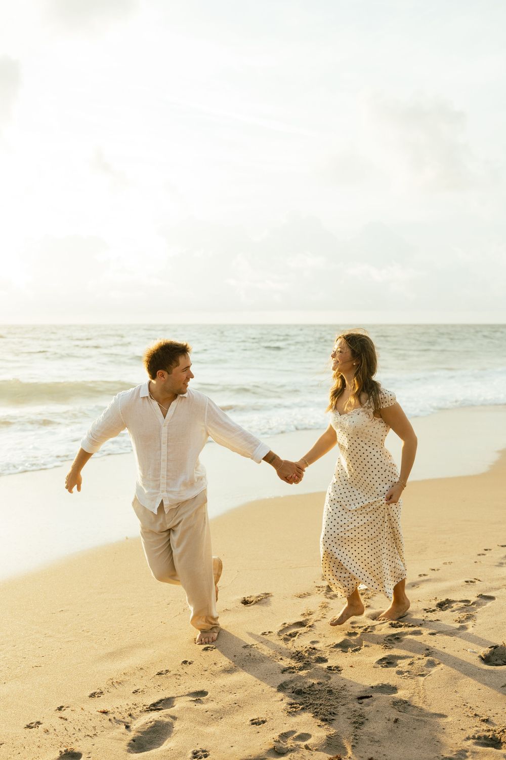 Playful sunrise beach engagement photos with golden light and bright blue waters. Jacksonville Engagement Photographer - Lindsay McDow Photo