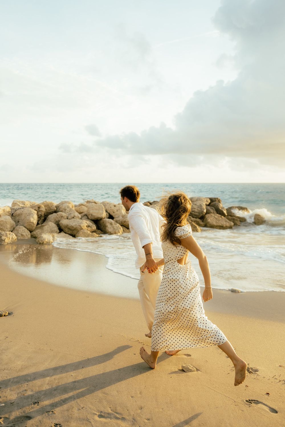 Playful sunrise beach engagement photos with golden light and bright blue waters. Jacksonville Engagement Photographer - Lindsay McDow Photo