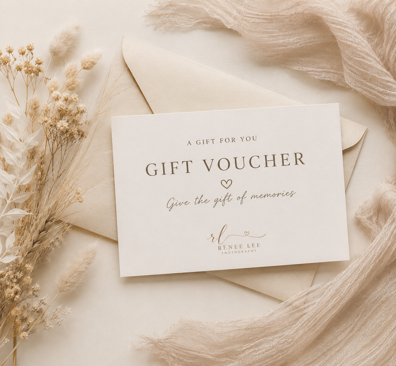 Elegant gift voucher card with heart detail on cream envelope, surrounded by dried flowers and soft fabric.