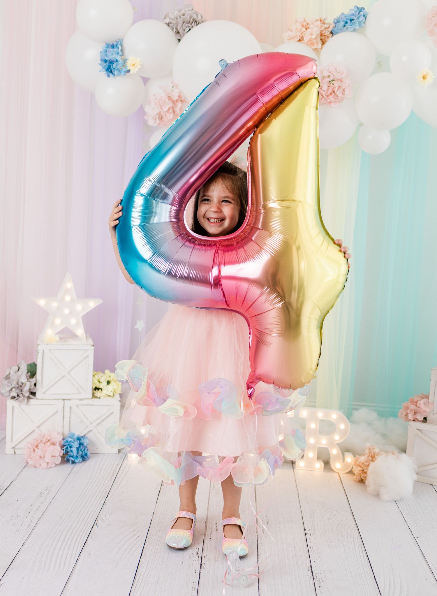 Elegant peach dress photoshoot with gold balloons and garland against white backdrop.