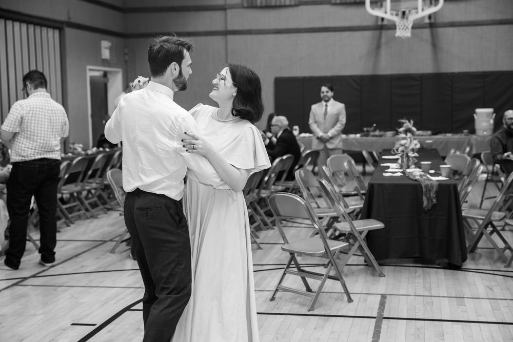 Couple sharing first dance at wedding reception in black and white photo.
