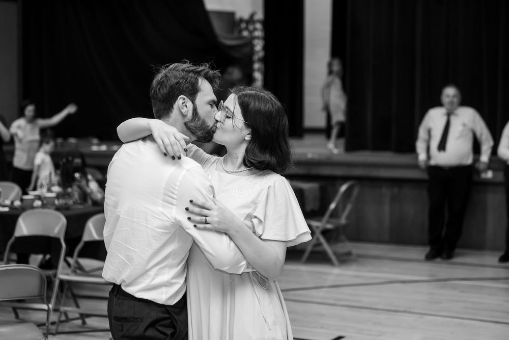 Newlyweds share a romantic kiss during first dance at wedding reception.