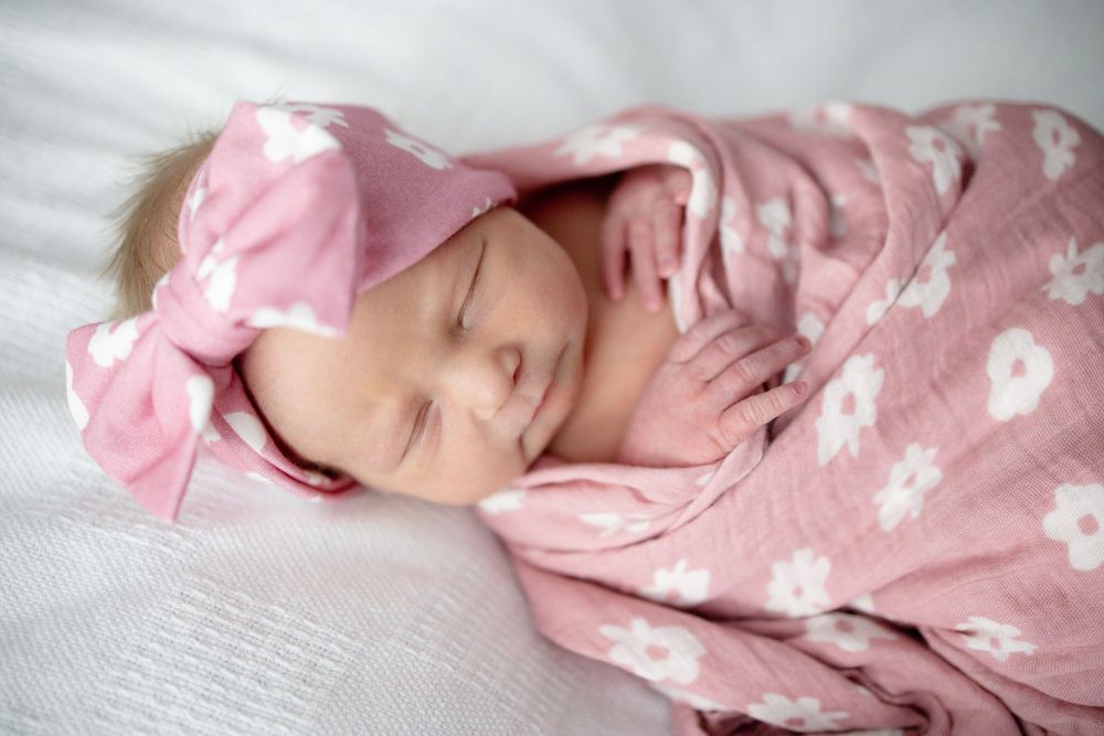 Sleeping newborn baby girl swaddled in pink floral blanket with matching bow headband at Parkwest Medical Center in Knoxville, TN.