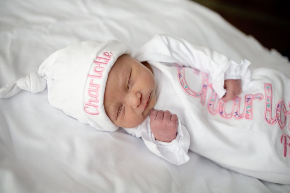 Newborn baby named Charlotte sleeping peacefully in a white personalized gown and matching hat at Parkwest Medical Center in Knoxville, TN.