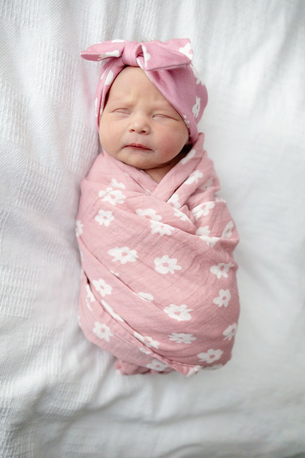 Newborn baby girl swaddled in pink floral muslin blanket with matching bow at Parkwest Medical Center in Knoxville, TN.