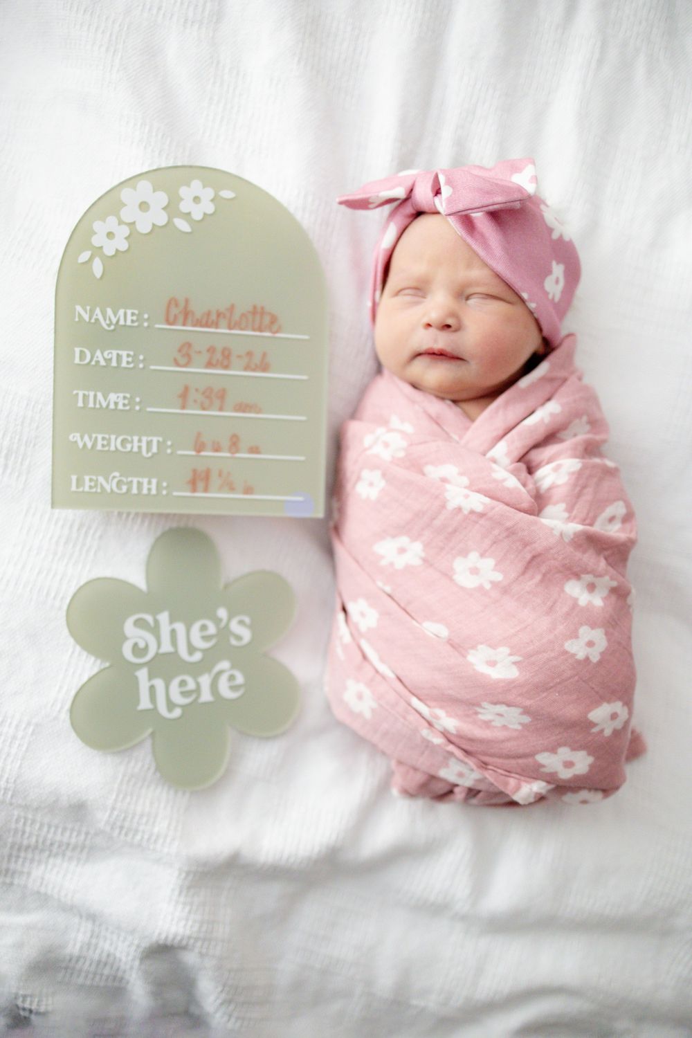 Newborn swaddled in pink floral blanket with birth stats sign and She's Here flower decoration at Parkwest Medical Center in Knoxville, TN.