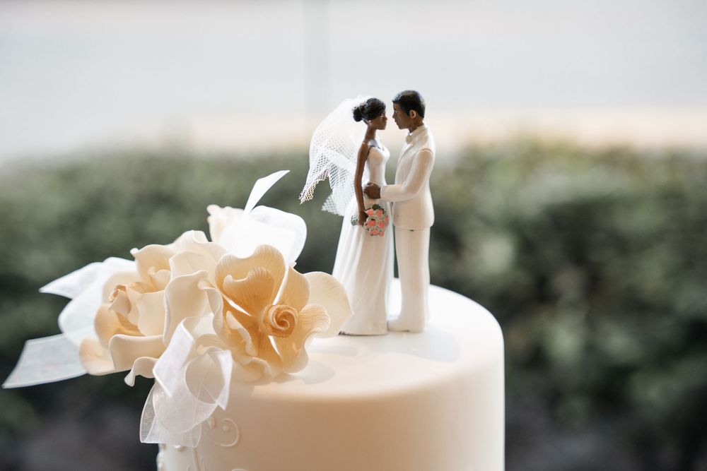 Close-up of a wedding cake topper featuring bride and groom figurines surrounded by elegant white flowers.