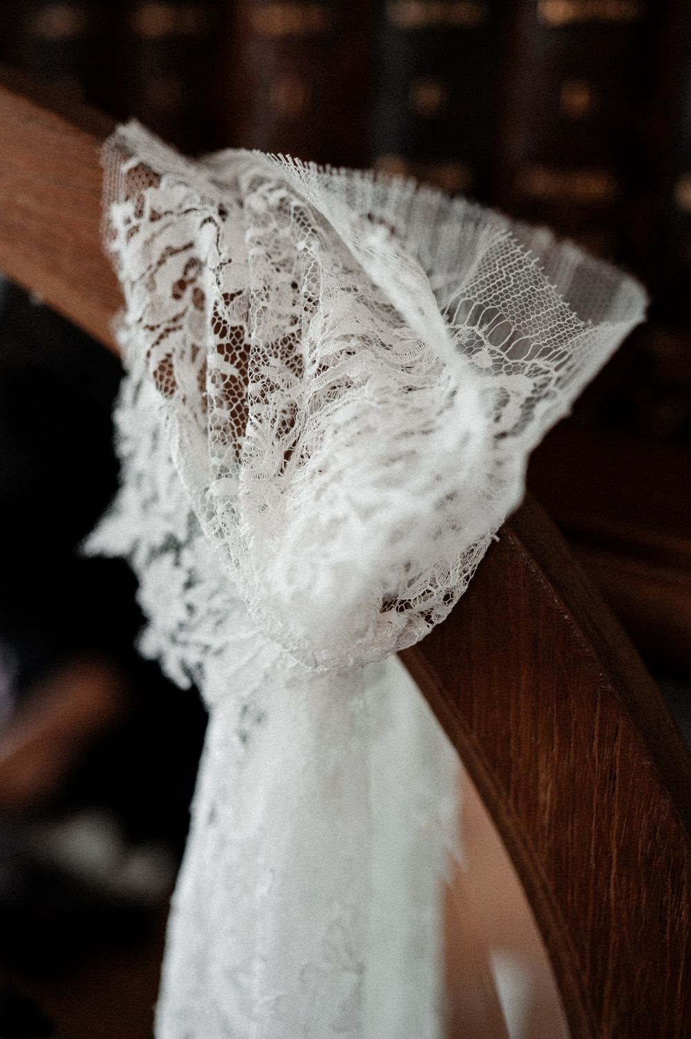 Elegant white lace and tulle bow decorating a wooden church pew for a wedding ceremony.