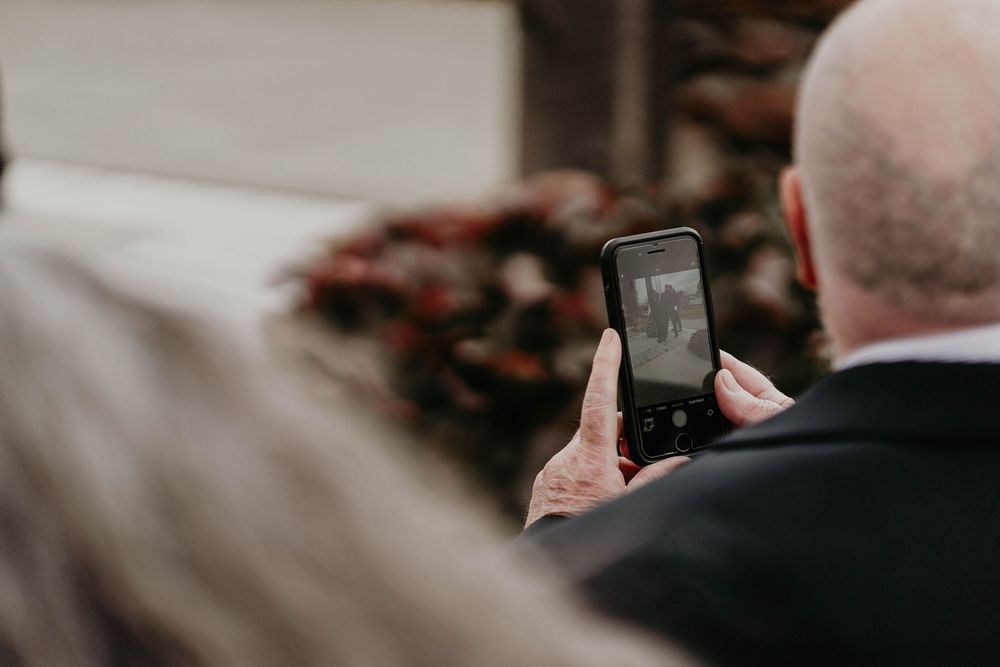 Person photographing a floral arrangement with a smartphone at a formal event or ceremony.