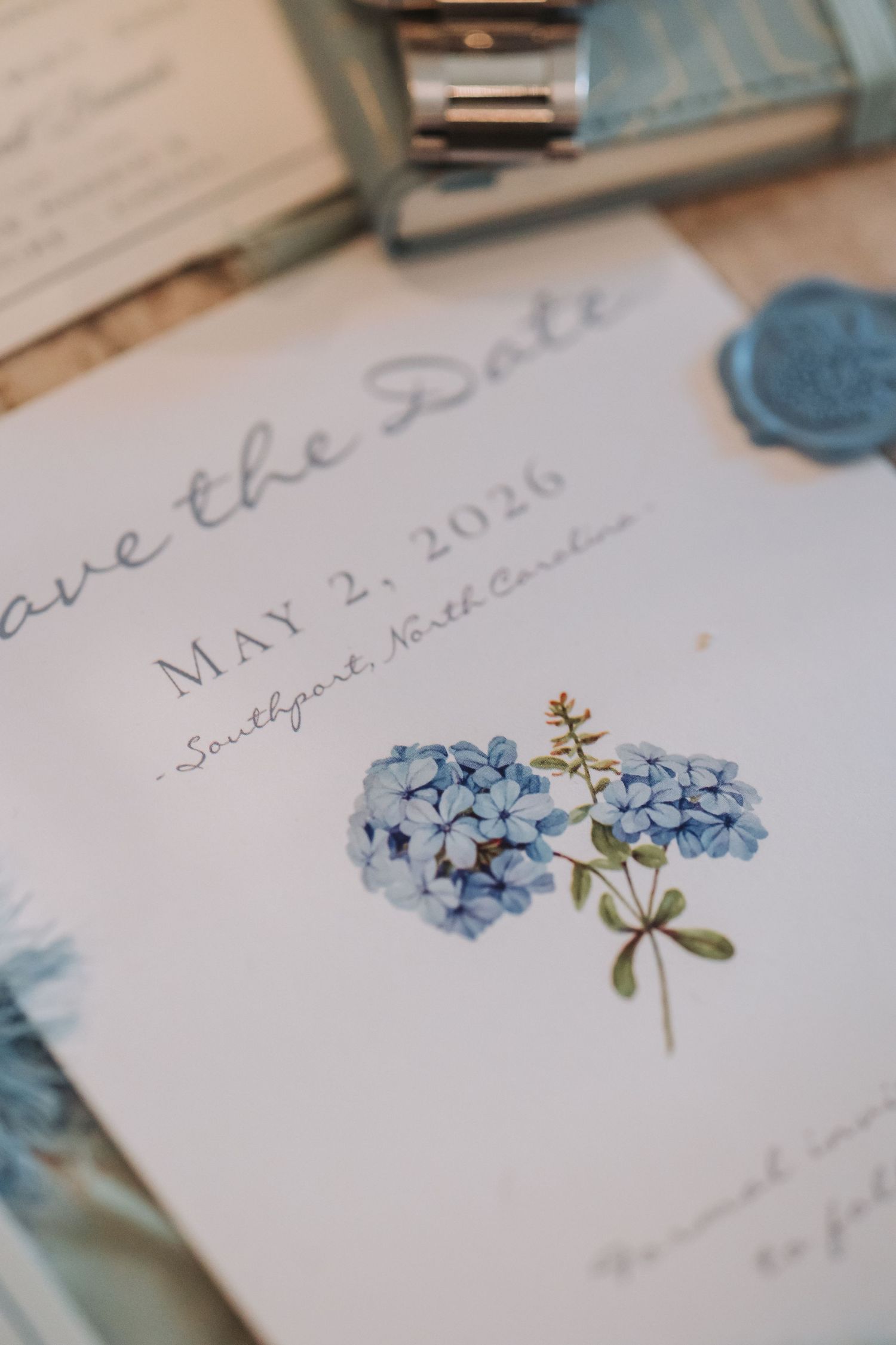 Blue hydrangea save the date card for May 2, 2026 wedding in Southport, North Carolina with wax seal.
